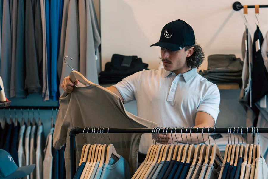Customer wearing a Point-branded cap selecting a t-shirt at The Point Clothing Lounge in Lynnfield, MA