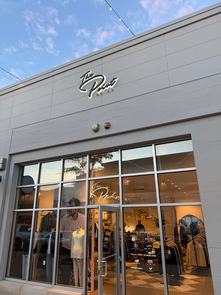 The Point Clothing Lounge storefront exterior in Lynnfield, MA, with illuminated sign and men's clothing displays visible through the windows