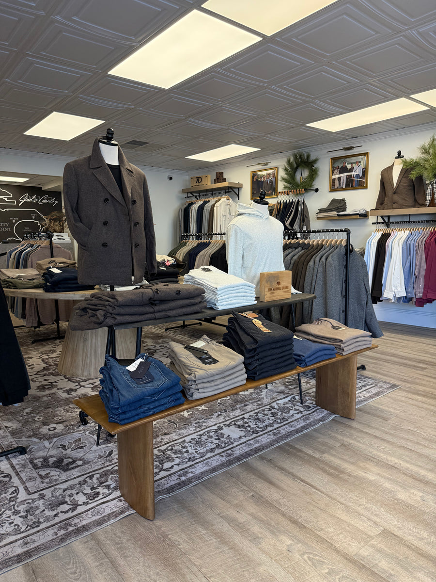 Menswear display inside The Point Clothing Lounge in South Boston, featuring folded sweaters, denim, and outerwear